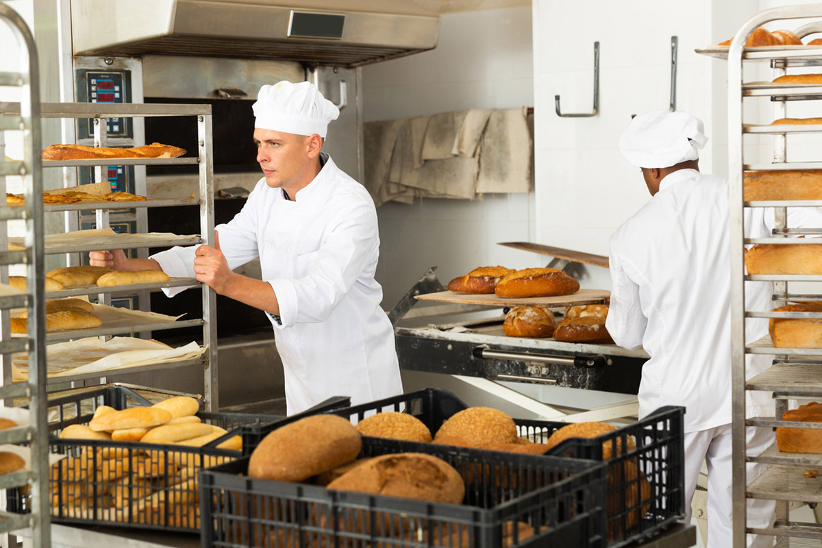 Two gentlemen in bakery kitchen with nesting racks