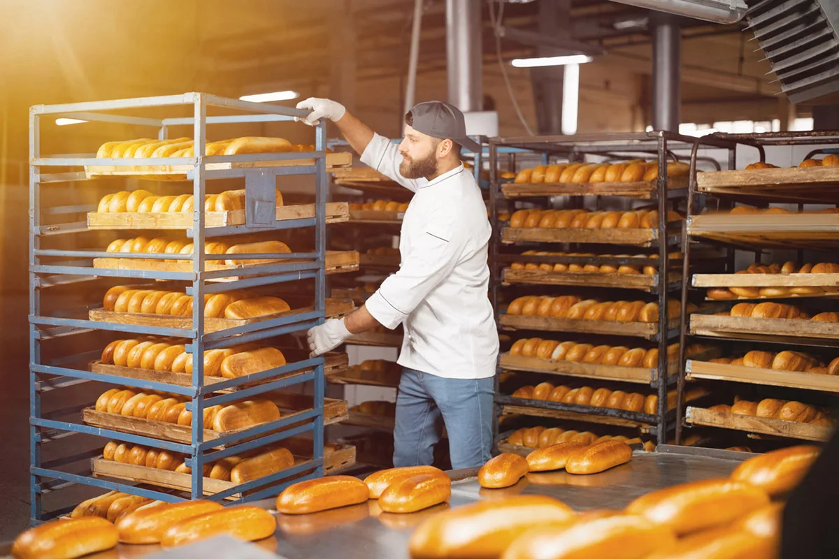 Chef with sheet pan racks full of bread