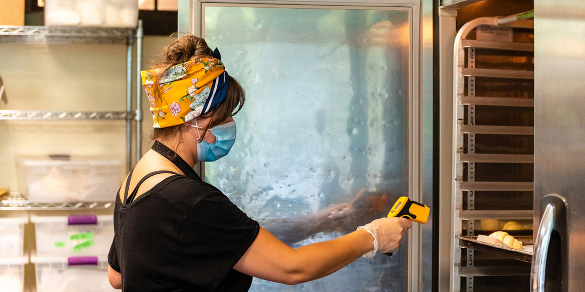 Woman checking temperature on commercial bakery cooling rack