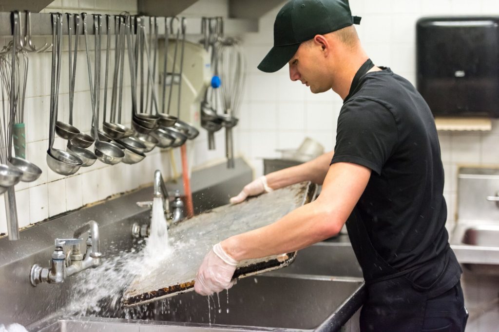 Kitchen staff cleaning steel tray - How to stop stainless steel rusting