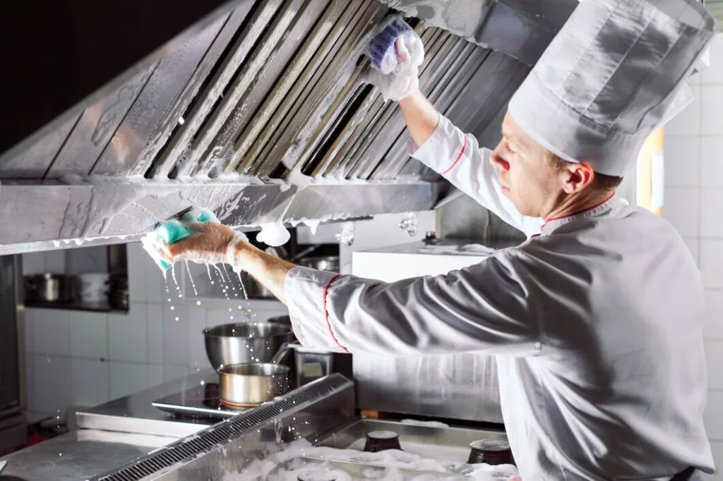 chef cleaning stainless steel extraction fan